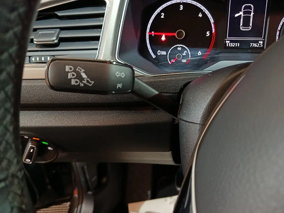 Gros plan sur la manette de clignotants et le tableau de bord numérique du Volkswagen T-Roc gris foncé, vue côté conducteur.