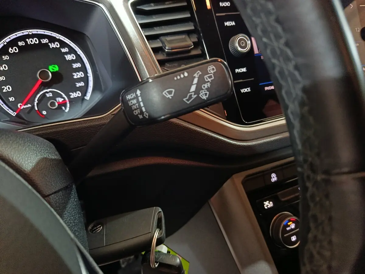 Gros plan intérieur sur le volant et le commodo d’essuie-glace du Volkswagen T-Roc 2.0 TDI 150 gris foncé, tableau de bord visible.