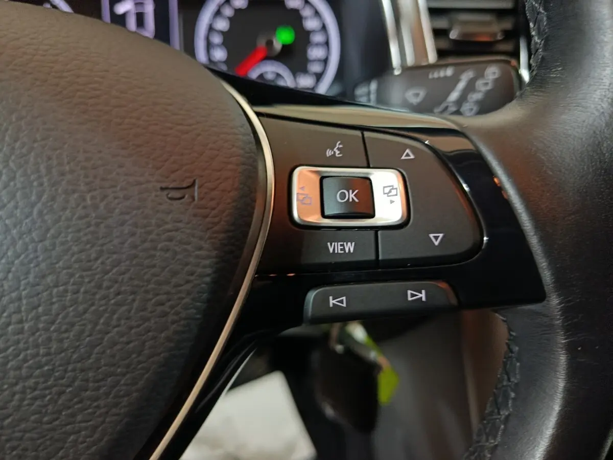 Gros plan sur les commandes multifonctions à droite du volant cuir du Volkswagen T-Roc gris foncé, tableau de bord en arrière-plan.