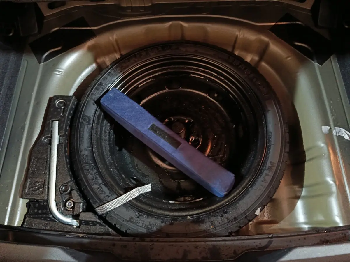 Vue rapprochée de la roue de secours et des outils dans le coffre d'un Volkswagen T-Roc gris foncé 2021.