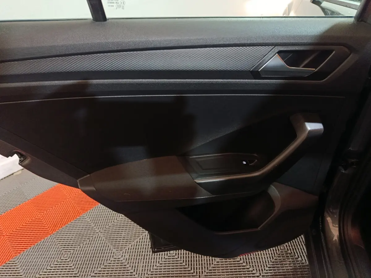 Vue intérieure côté gauche de la porte avant d’un Volkswagen T-Roc gris foncé, avec poignée et commande de lève-vitre.