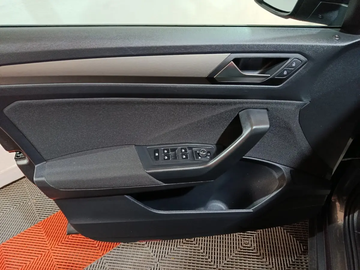 Vue intérieure du panneau de porte avant gauche du Volkswagen T-Roc gris foncé, avec commandes des vitres et verrouillage.