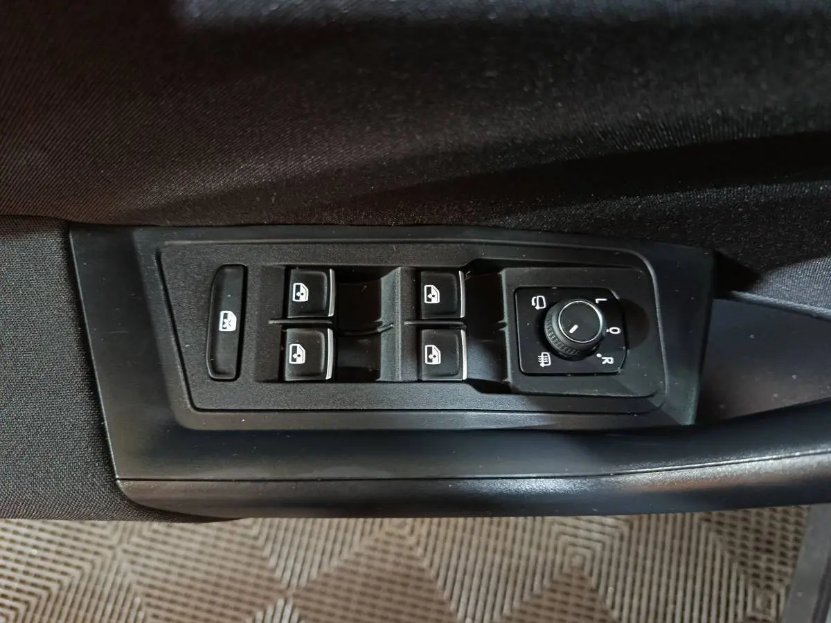 Panneau de commandes des vitres et rétroviseurs côté conducteur d’un Volkswagen T-Roc gris foncé, vue intérieure rapprochée.