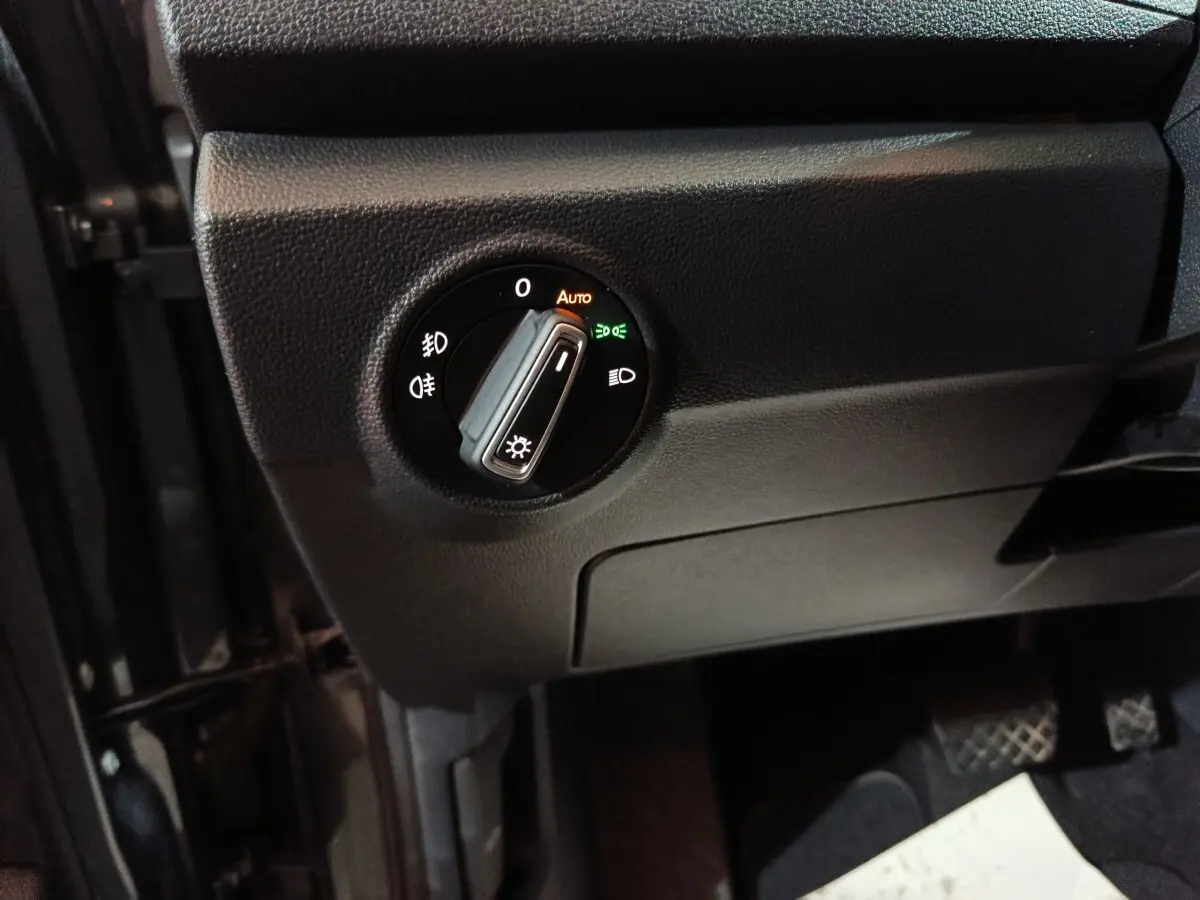 Gros plan sur le bouton de commande des phares du Volkswagen T-Roc gris foncé, côté conducteur, intérieur avant.