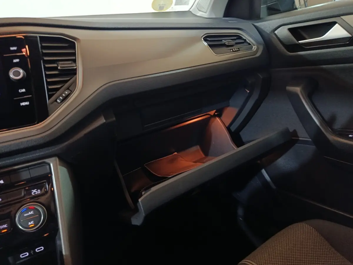 Intérieur du Volkswagen T-Roc 2021 gris foncé, vue côté passager avec boîte à gants ouverte et tableau de bord tactile.