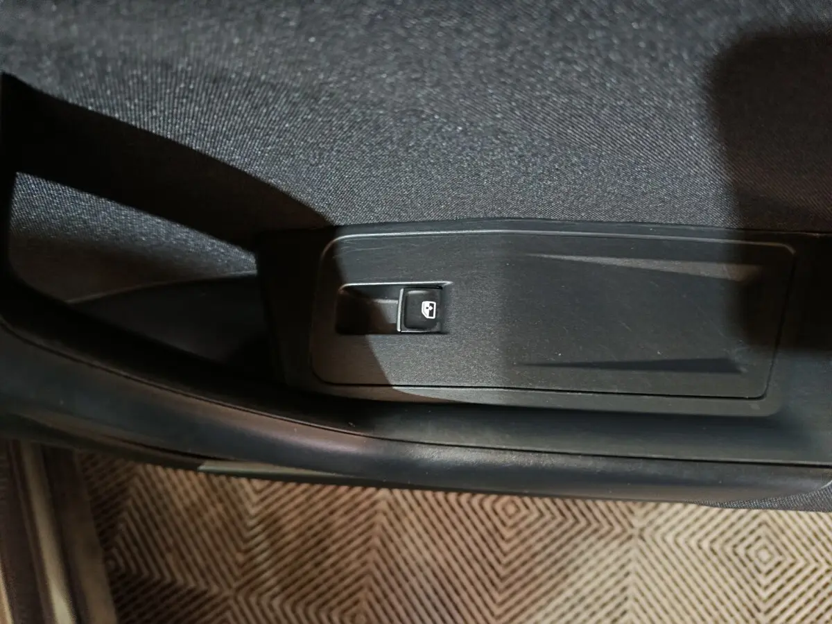 Gros plan sur le levier d'ouverture de trappe à carburant dans l'habitacle du Volkswagen T-Roc gris foncé.