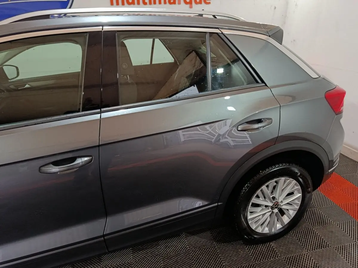 Vue latérale droite du Volkswagen T-Roc gris foncé, mettant en valeur les jantes alliage et les contours de fenêtres chromés.