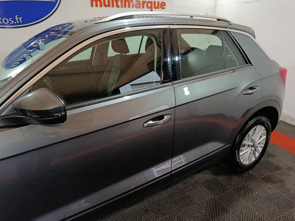 Vue latérale droite d’un Volkswagen T-Roc gris foncé, mettant en valeur les vitres teintées et les jantes alliage.