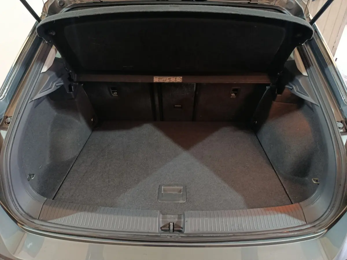 Coffre ouvert vu de l'arrière d'un Volkswagen T-Roc gris foncé, espace de chargement propre et vide.