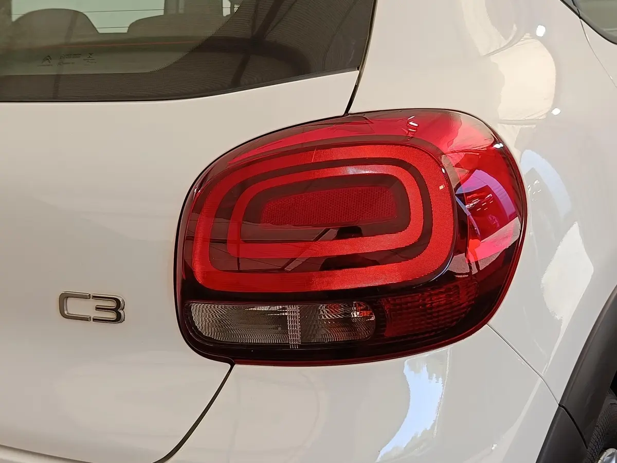 Gros plan sur le feu arrière droit rouge et le logo C3 d'une Citroën C3 blanche vue de l'arrière.