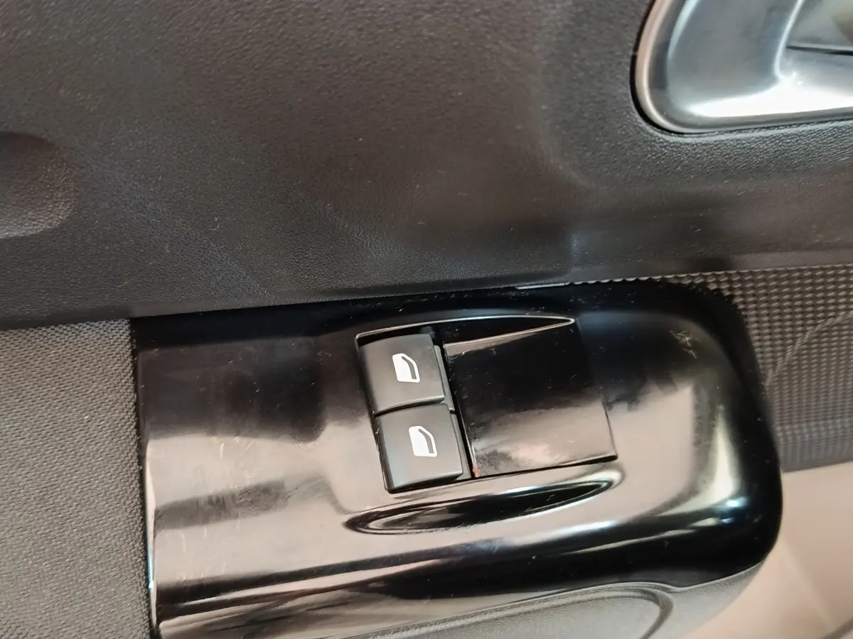 Gros plan sur les commandes de lève-vitres électriques côté conducteur d'une Citroën C3 blanche de 2020.