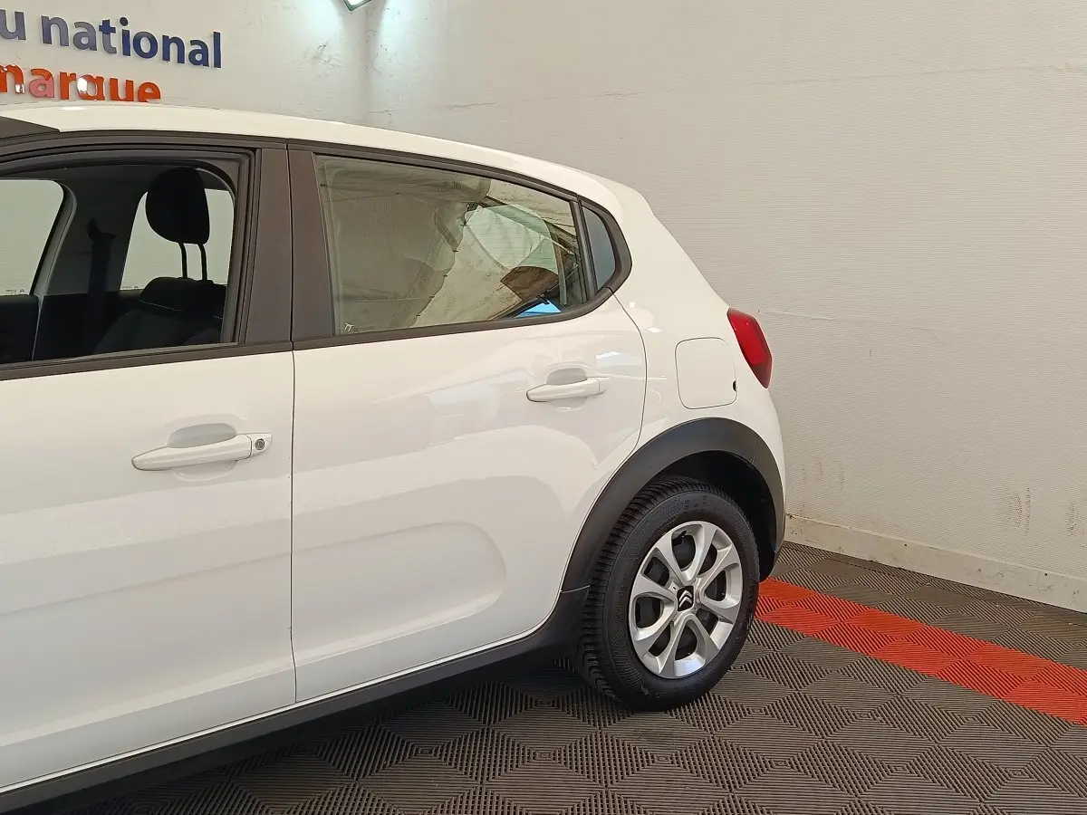 Vue latérale droite d'une Citroën C3 blanche, mettant en valeur les jantes alliage et les protections noires autour des passages de roue.