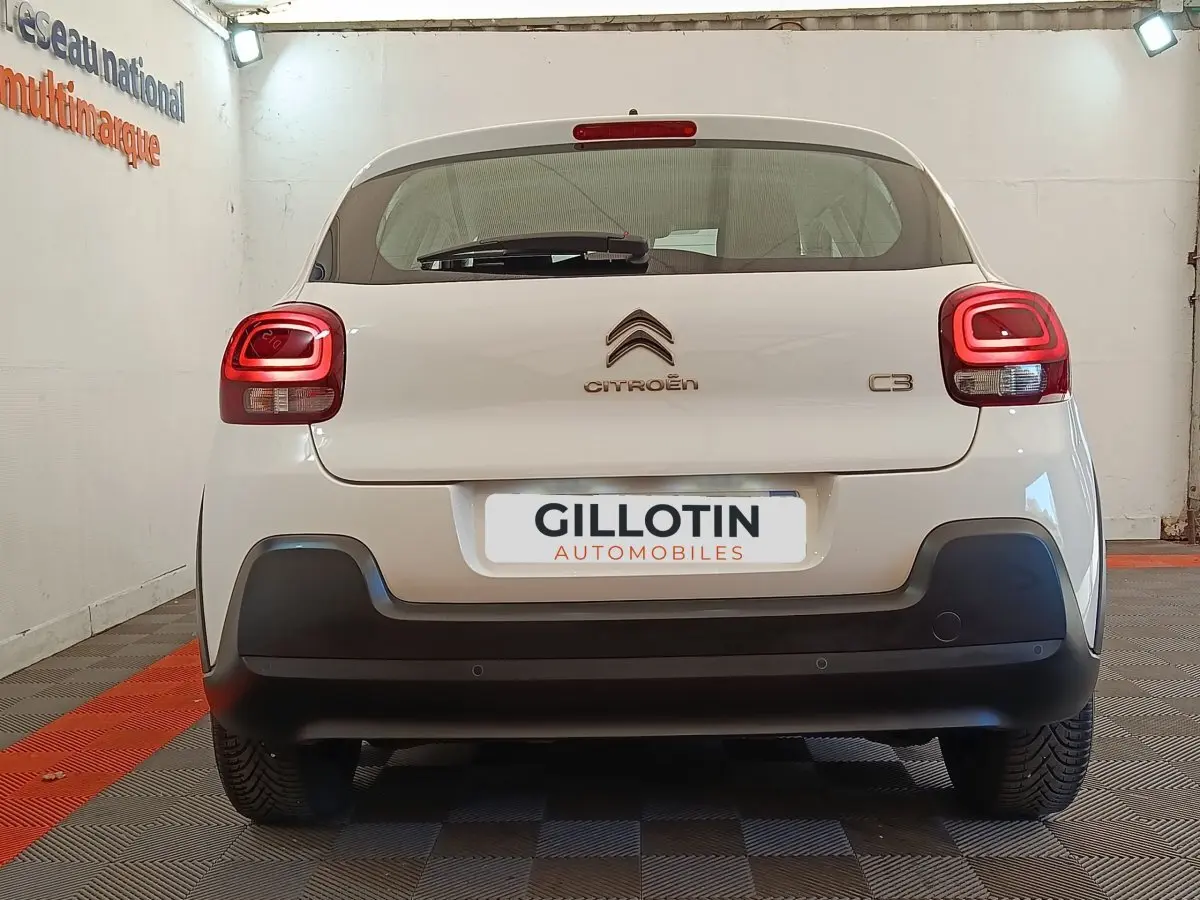 Vue arrière d'une Citroën C3 blanche avec feux arrière LED et pare-chocs noir mat dans un garage.