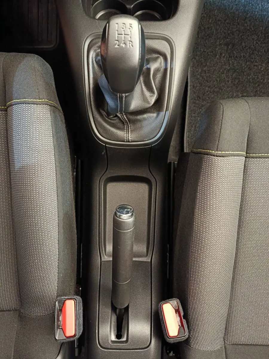 Vue plongeante sur la console centrale de la Citroën C3 2020, montrant levier de vitesse manuel et frein à main entre sièges gris.