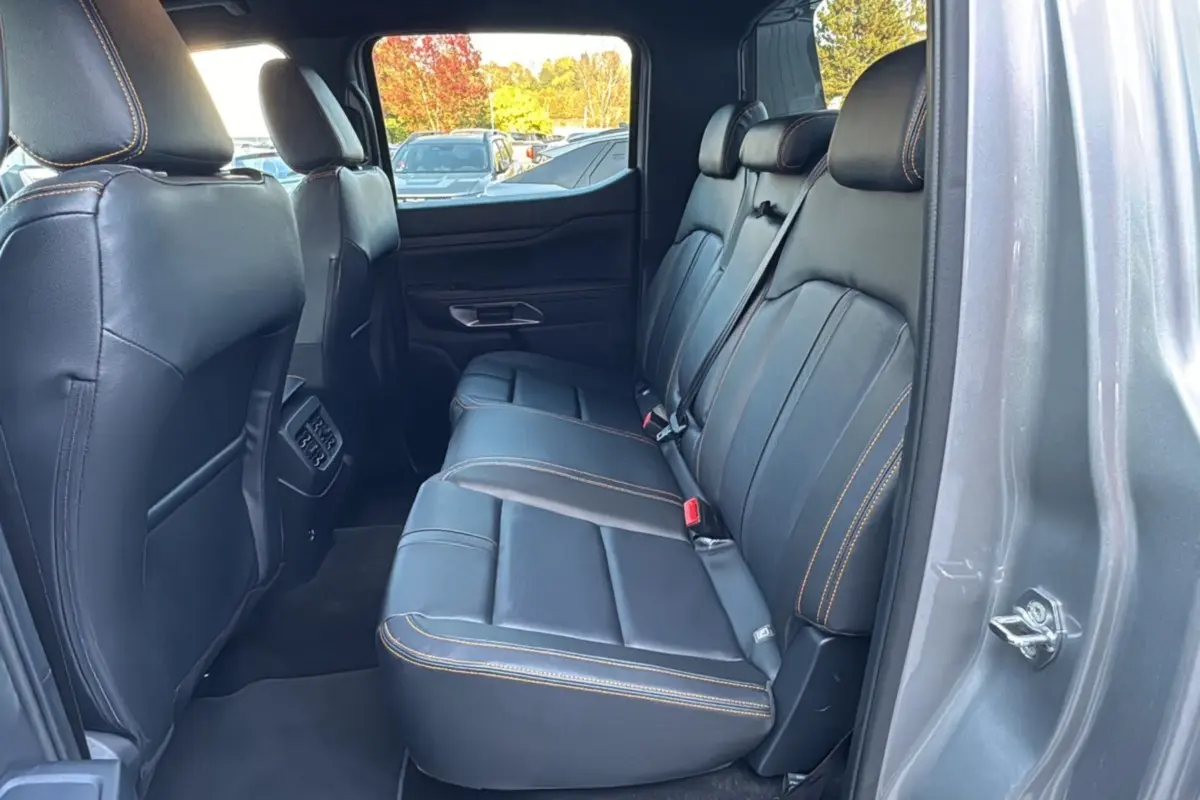 Vue intérieure côté droit des sièges arrière en cuir noir avec surpiqûres orange du Ford Ranger 2026 gris iconic Wildtrak Plus.