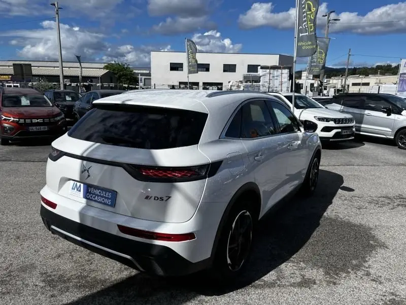 Vue 3/4 arrière droite d'un DS7 Crossback blanc 2019 HDI 130 Performance Line avec feux arrière LED et vitres teintées.