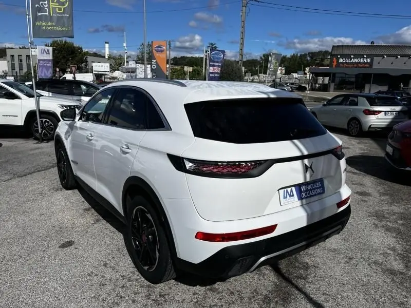 Vue 3/4 arrière droite d'un DS7 Crossback blanc 2019, version HDI 130 Performance Line avec feux arrière distinctifs.