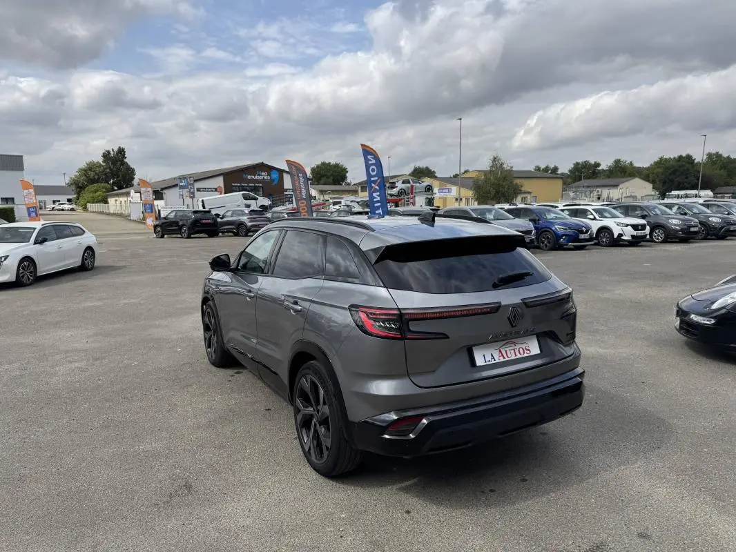 Renault Austral gris 3/4 arrière droit, vitres surteintées et jantes aluminium noires sur parking.