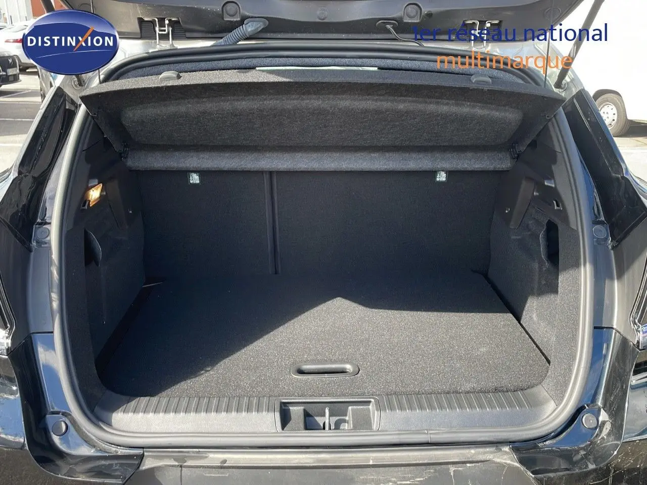 Coffre ouvert vu de l'arrière d'un Renault Captur noir étoile métal avec toit gris, montrant un espace de chargement propre et spacieux.