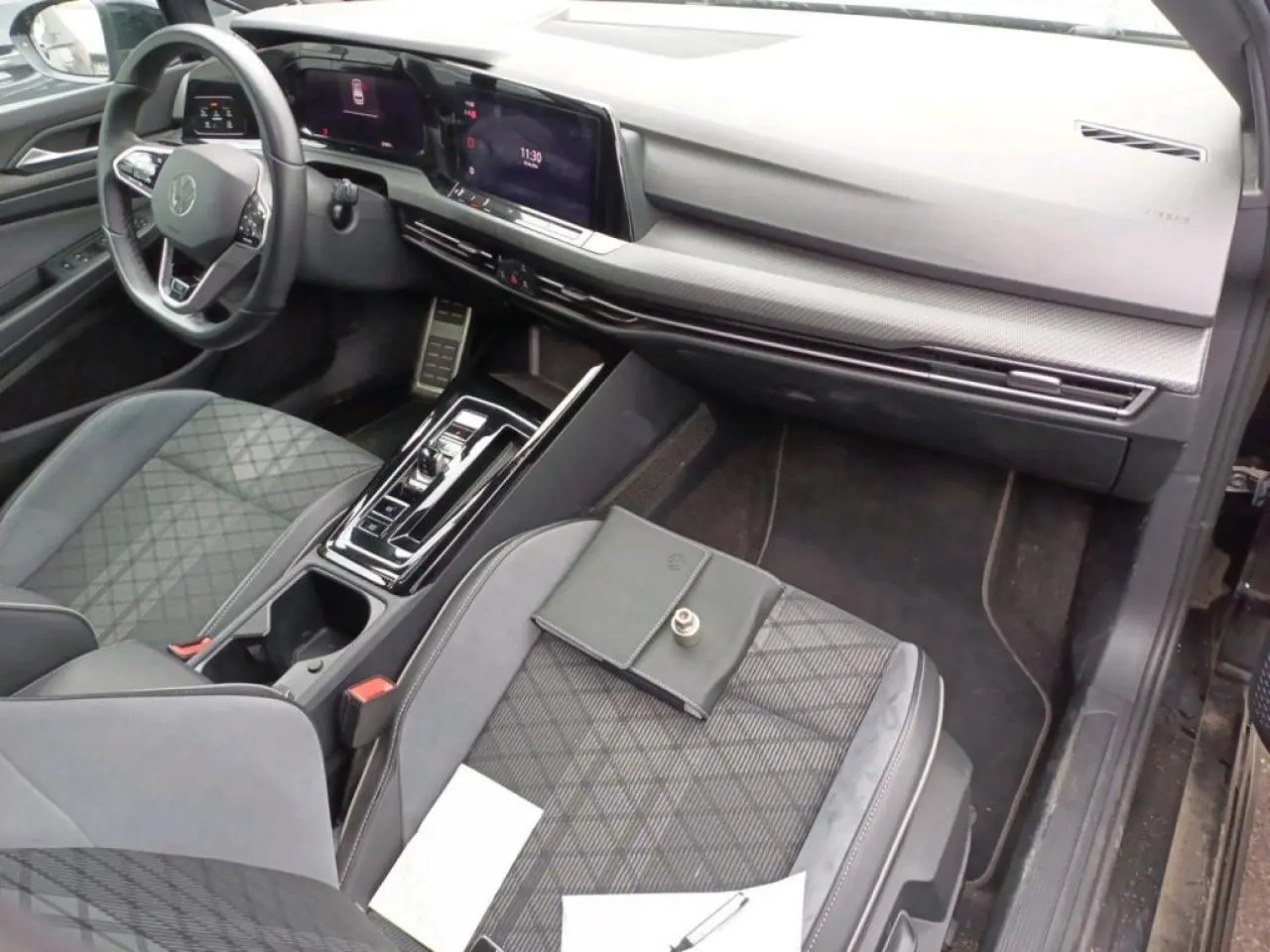 Vue intérieure côté passager avant de la Volkswagen Golf 8 R-Line 2024 avec sellerie tissu noire et console centrale moderne.