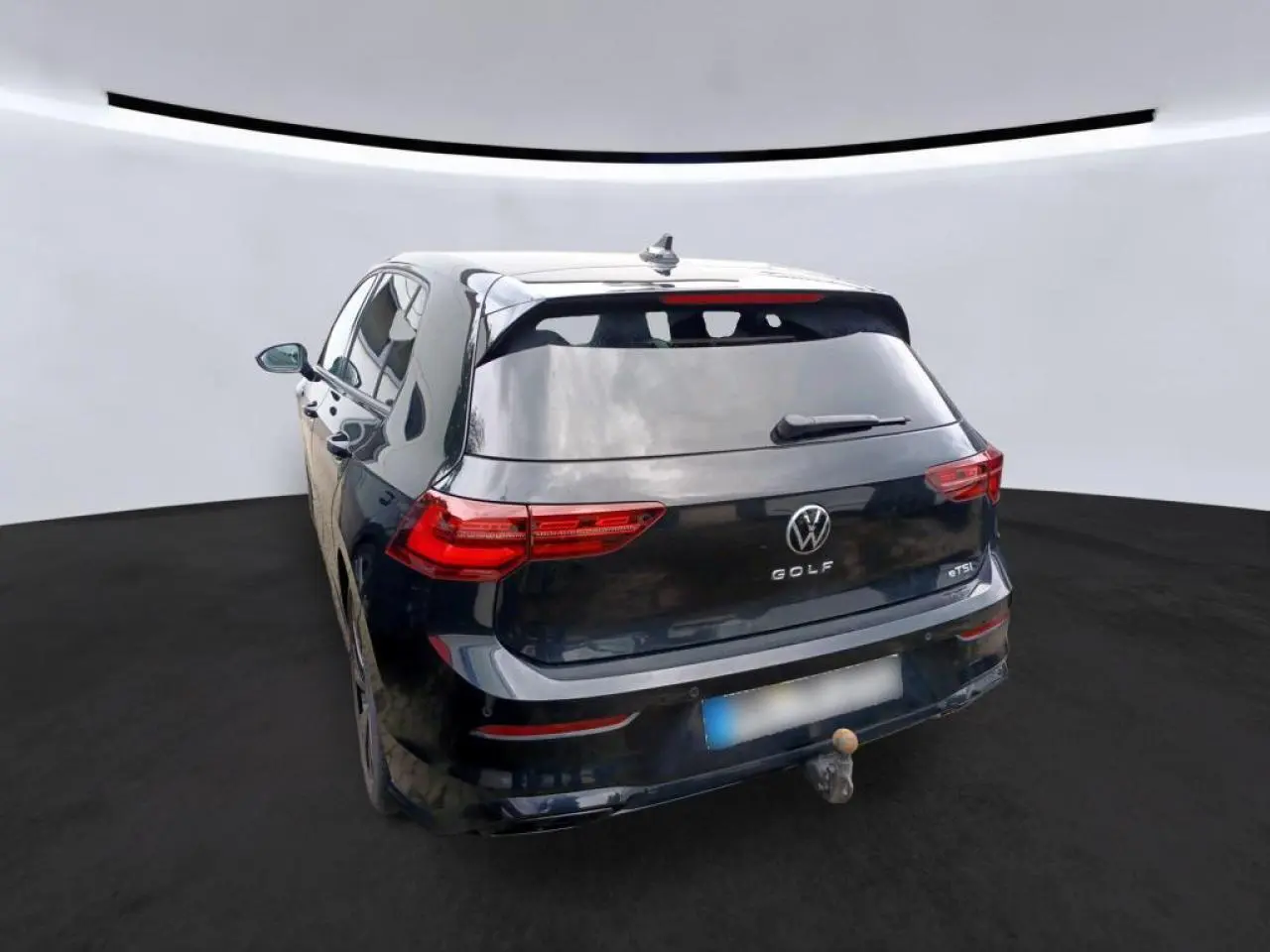 Volkswagen Golf 8 noir vue 3/4 arrière avec attelage escamotable et feux arrière LED défilants.