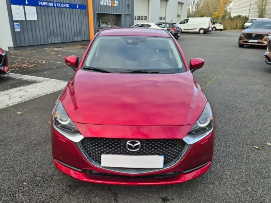 Vue frontale d'une Mazda2 rouge vif 2021 avec calandre noire et phares LED distinctifs.