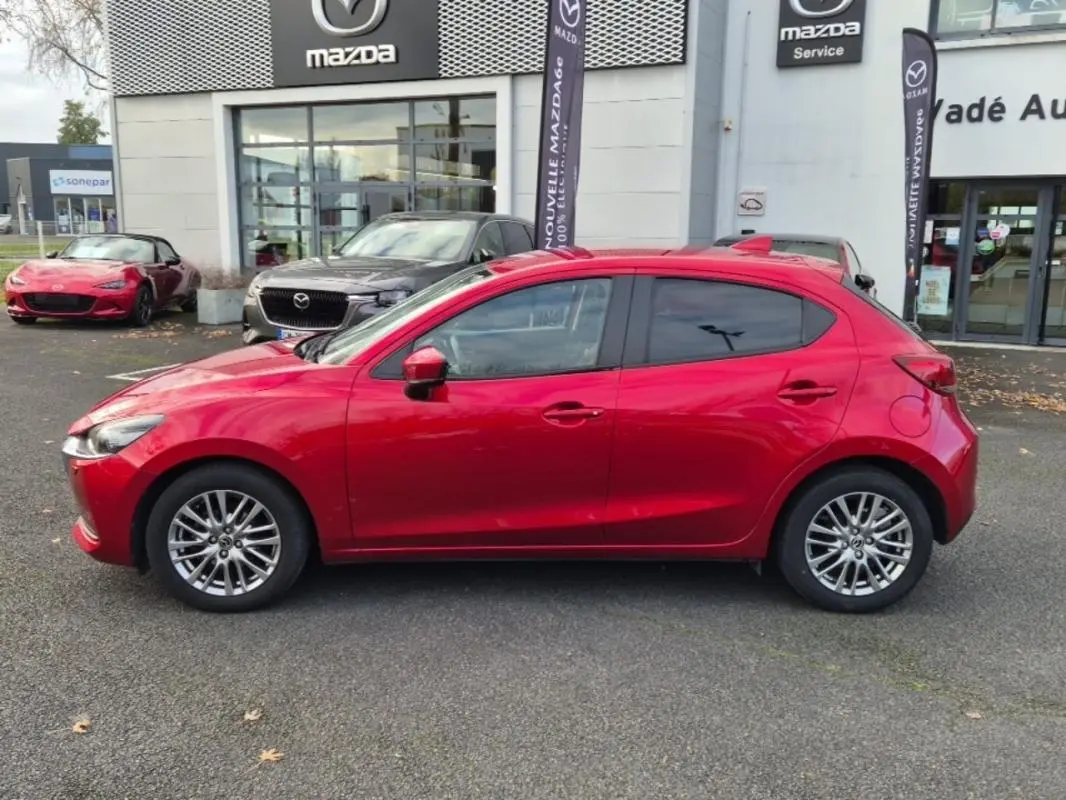 Vue latérale droite d'une Mazda2 rouge 2021 avec jantes aluminium, vitres surteintées et rétroviseurs assortis.