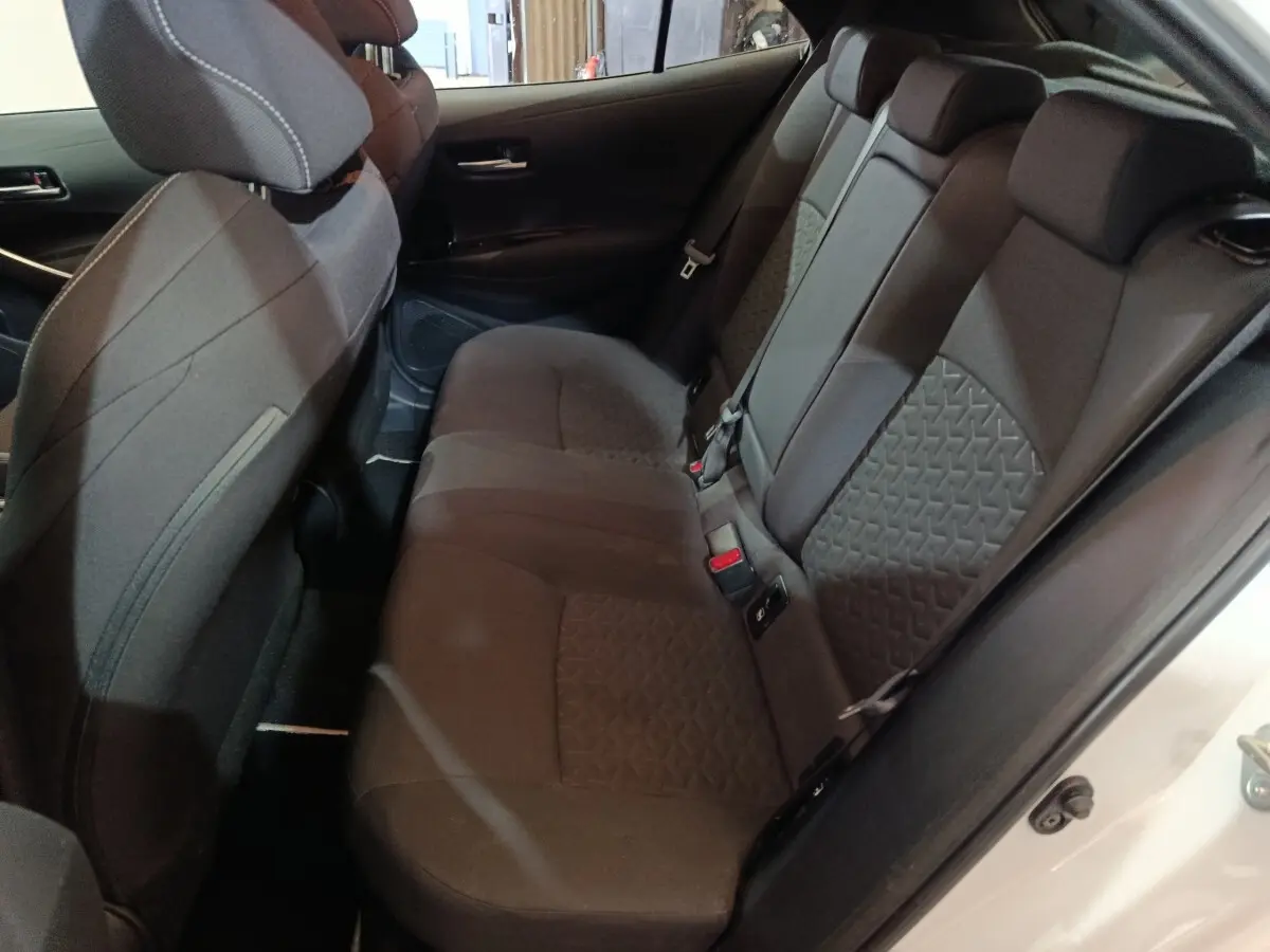 Vue intérieure côté droit sur la banquette arrière noire de la Toyota Corolla Hybride 2022, porte ouverte blanche visible.