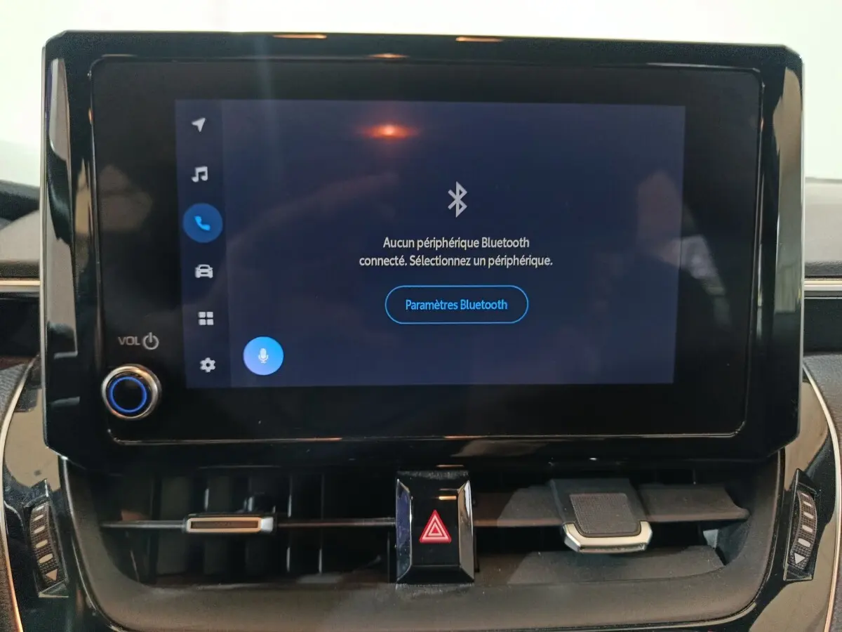 Écran tactile central allumé avec menu Bluetooth sur le tableau de bord de la Toyota Corolla hybride blanche.