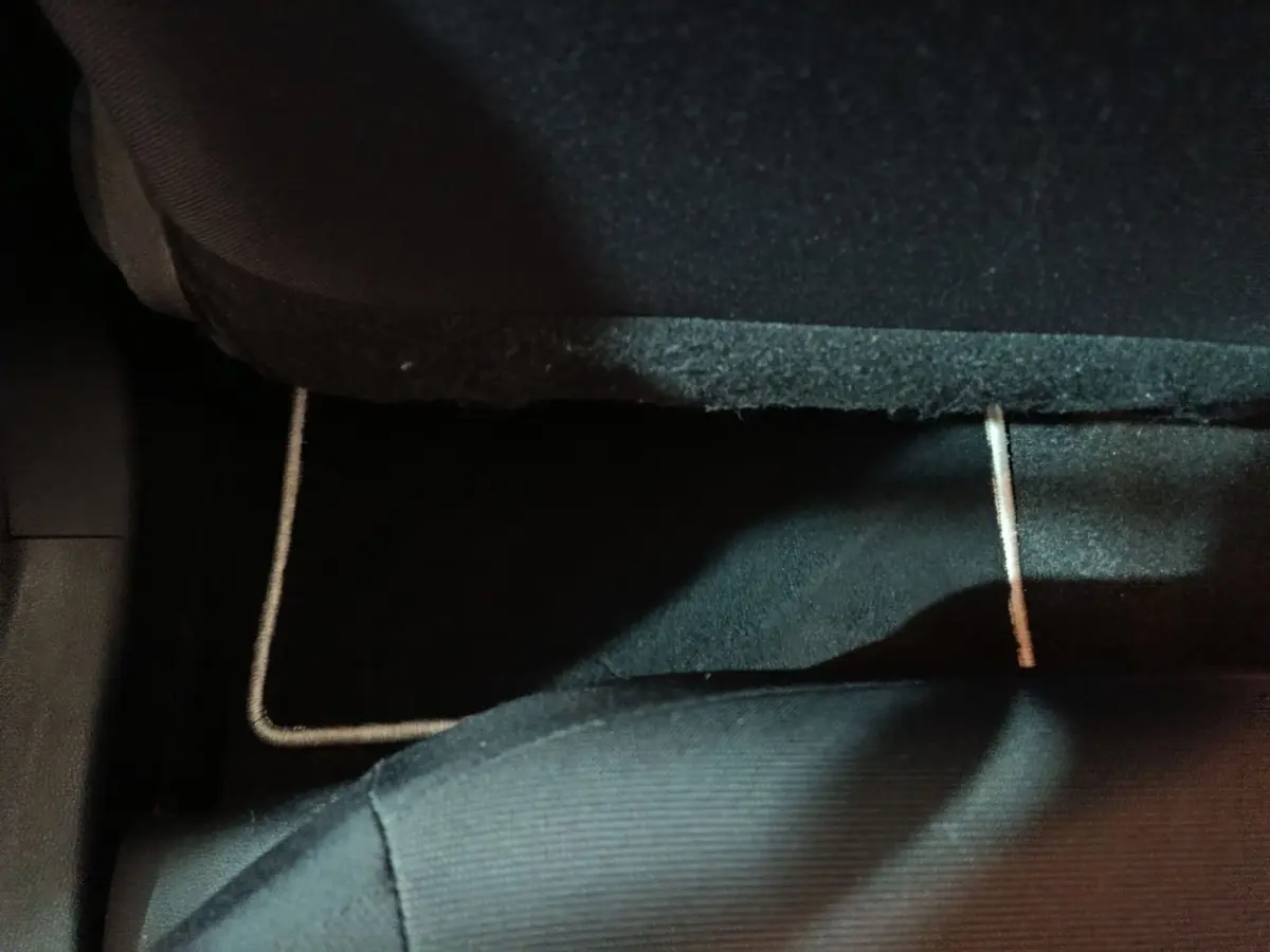 Vue rapprochée du tapis de sol noir sous le siège arrière d'une Toyota Corolla hybride blanche de 2022.