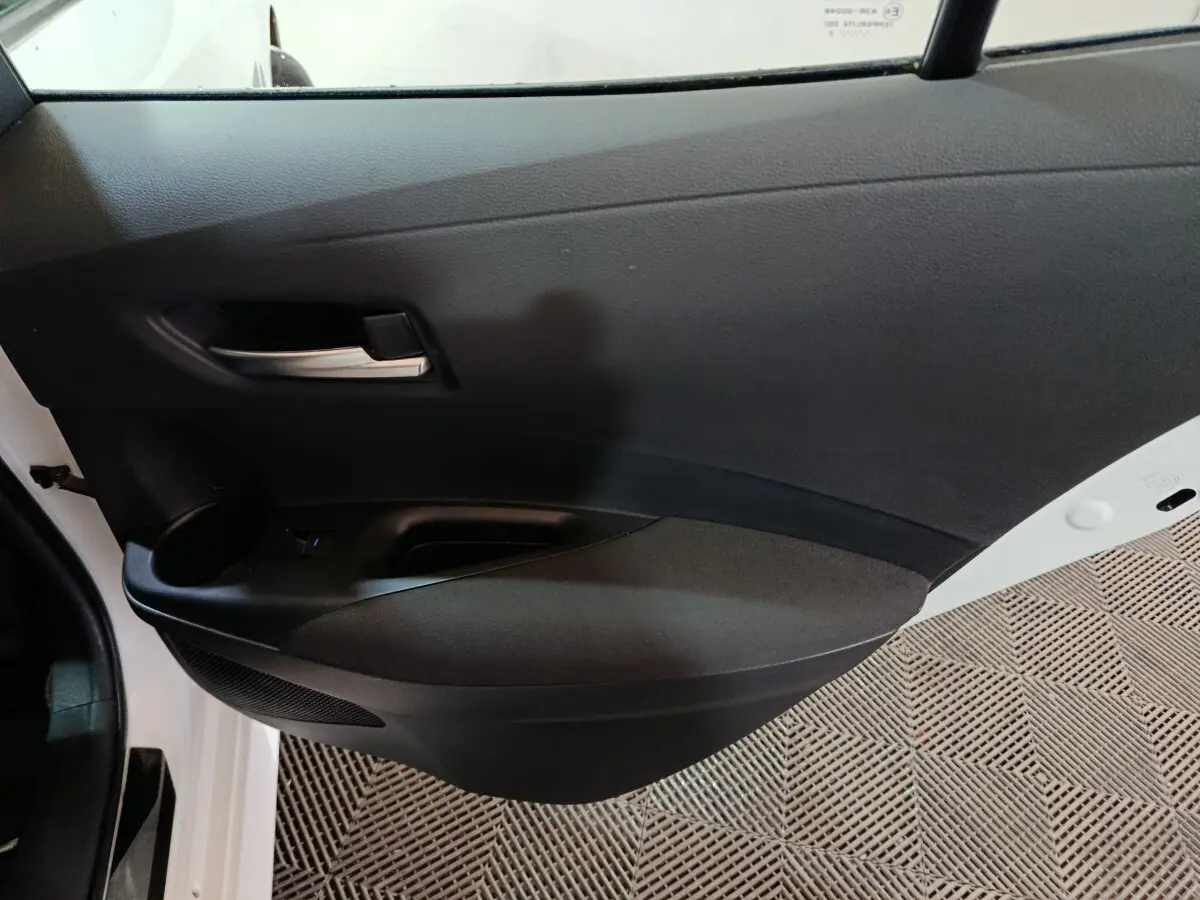 Vue intérieure côté gauche de la porte avant noire d'une Toyota Corolla hybride blanche 2022 avec poignée argentée.