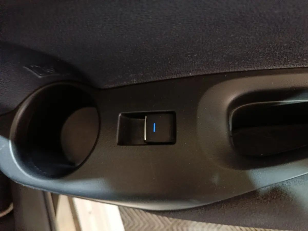 Bouton de commande électrique de la fenêtre sur la porte intérieure côté conducteur d'une Toyota Corolla blanche hybride.