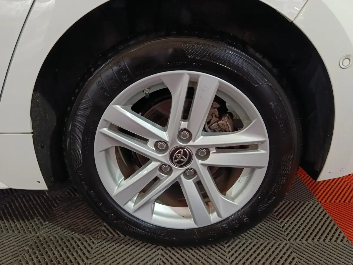 Gros plan sur la roue avant gauche blanche d'une Toyota Corolla hybride 2022 avec jante alliage argentée.