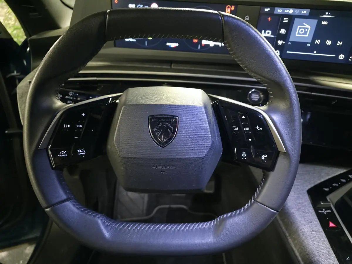 Volant cuir noir de la Peugeot 5008 2025 avec commandes intégrées et tableau de bord numérique en arrière-plan.