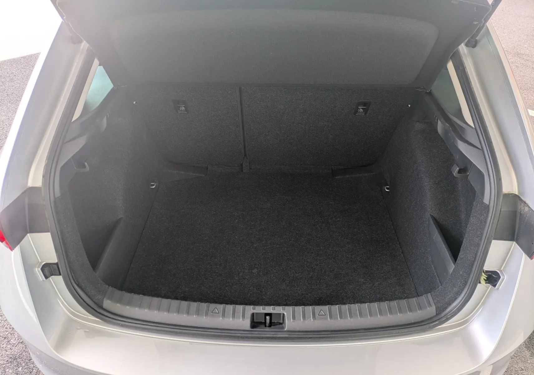 Coffre ouvert vu de l'arrière d'une Skoda Scala gris reflex, montrant l'espace de chargement vide et propre.