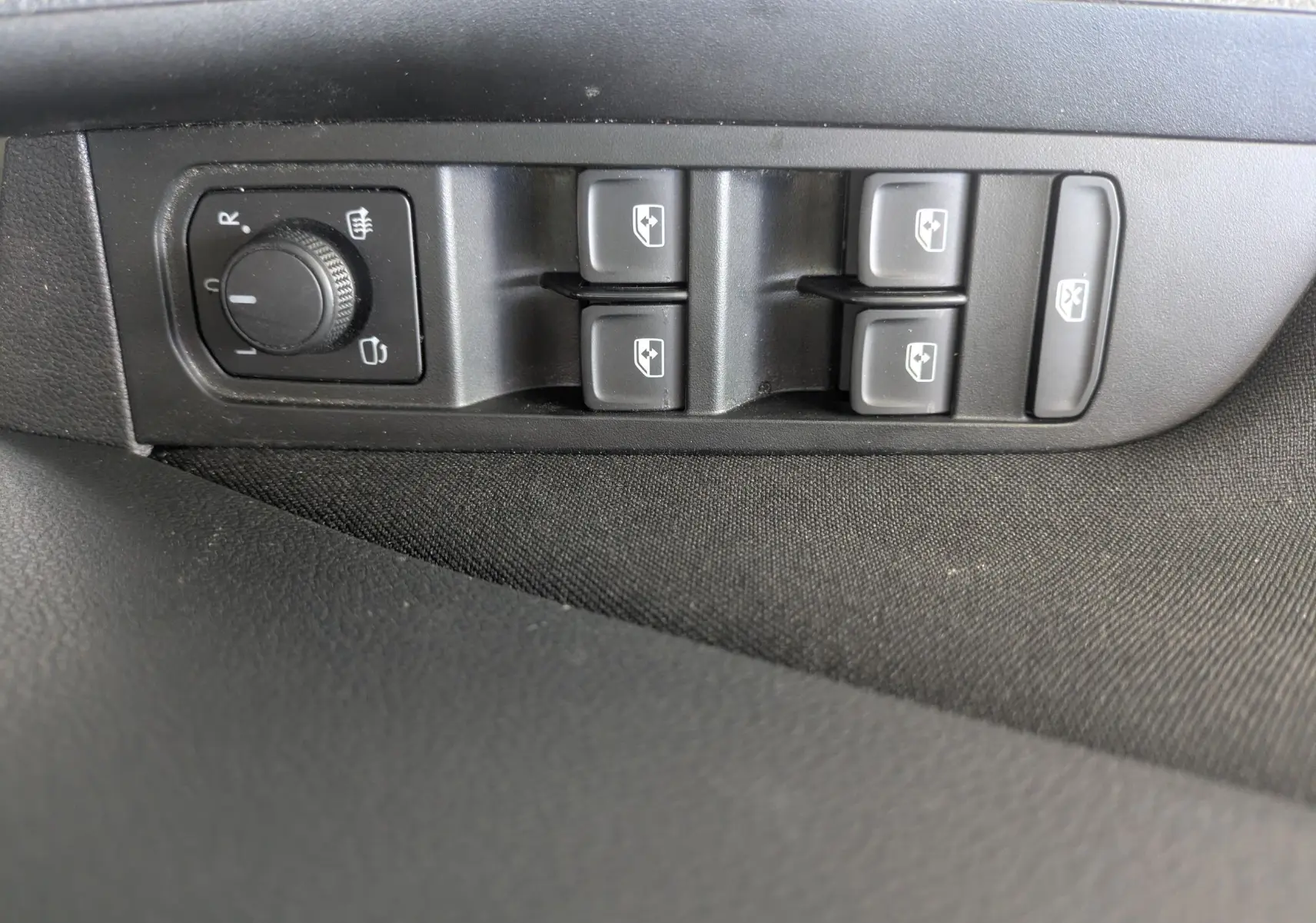 Gros plan sur les commandes de lève-vitres et réglage des rétroviseurs côté conducteur du Skoda Scala gris Reflex.