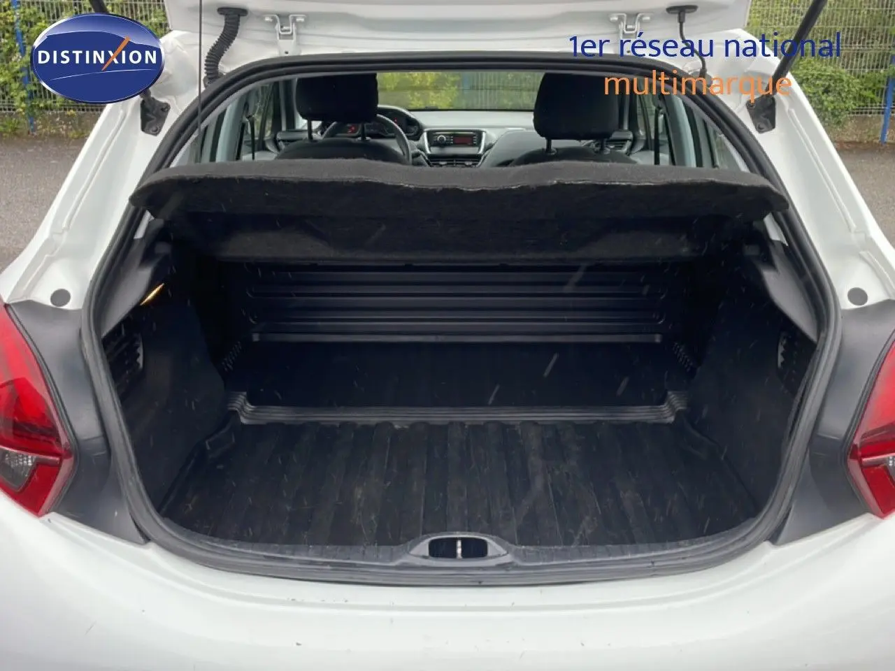 Coffre ouvert vu de l'arrière d'une Peugeot 208 Société blanc banquise, montrant l'espace de chargement vide.