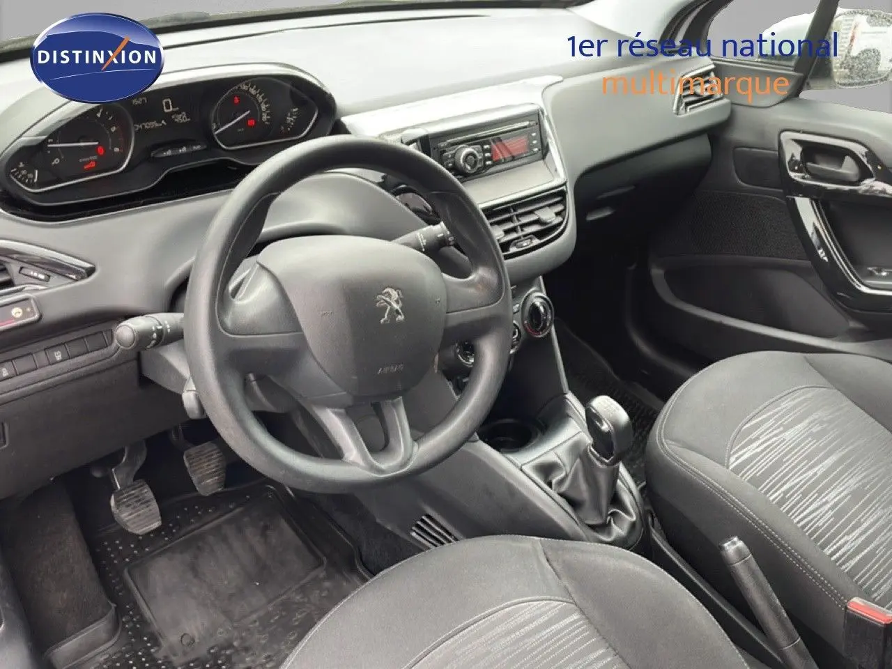 Vue intérieure de la Peugeot 208 Société 2018, tableau de bord et volant noirs avec détails tissu gris sur les sièges.