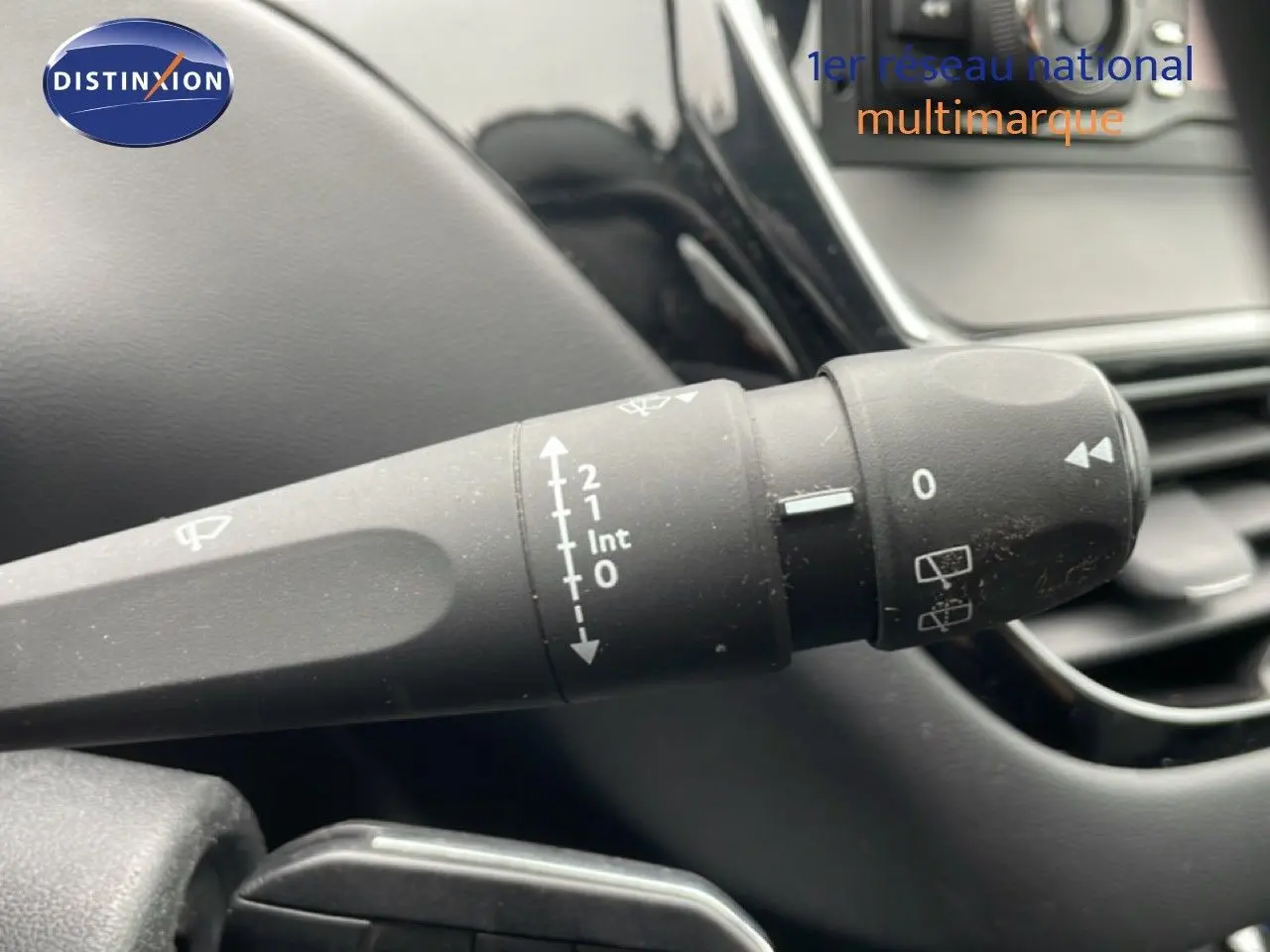 Gros plan sur la commande d’essuie-glace à gauche du volant dans l’habitacle noir d’une Peugeot 208 Blanc Banquise.