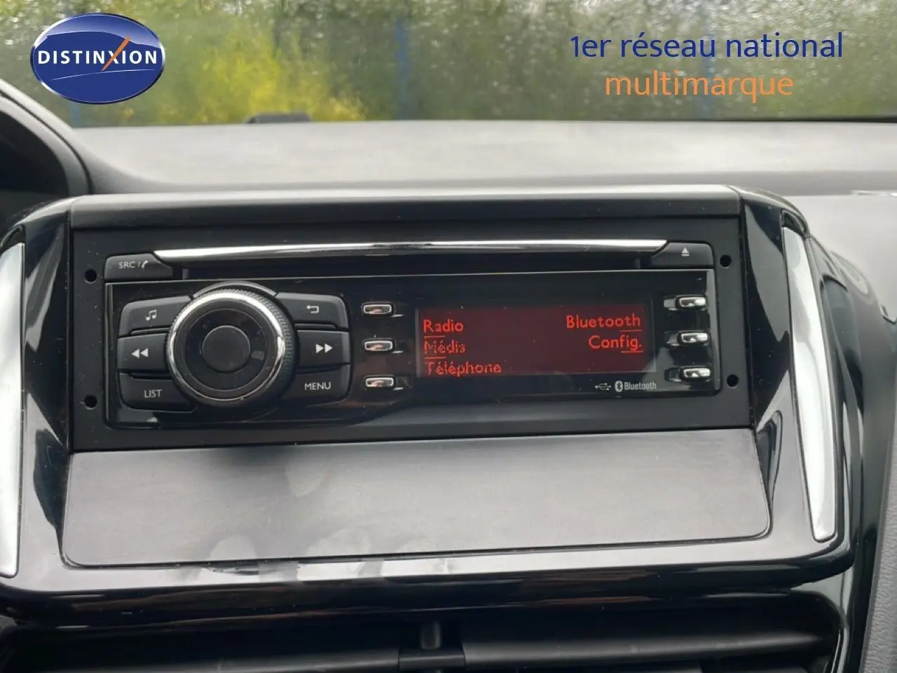 Gros plan sur la console centrale noire de la Peugeot 208 Société 2018, affichant l’écran radio avec options Bluetooth et média.