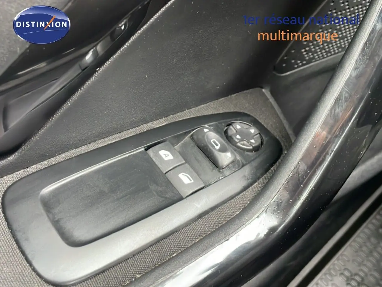 Gros plan sur les commandes de lève-vitres et réglage des rétroviseurs côté conducteur d'une Peugeot 208 Société blanche.