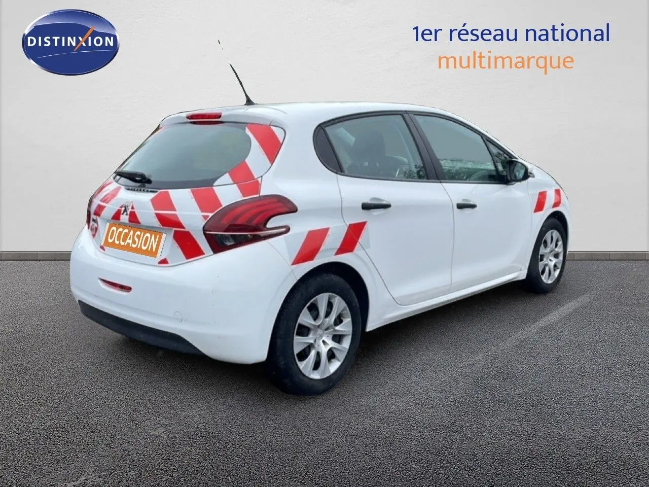 Vue 3/4 arrière droite d’une Peugeot 208 Société blanche avec marquages rouges et blancs, en stationnement sur sol gris.