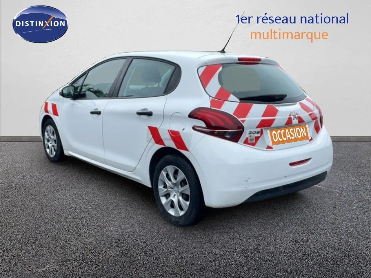 Vue 3/4 arrière droite d'une Peugeot 208 Société blanche avec bandes rouges diagonales et plaque "OCCASION" sur hayon.