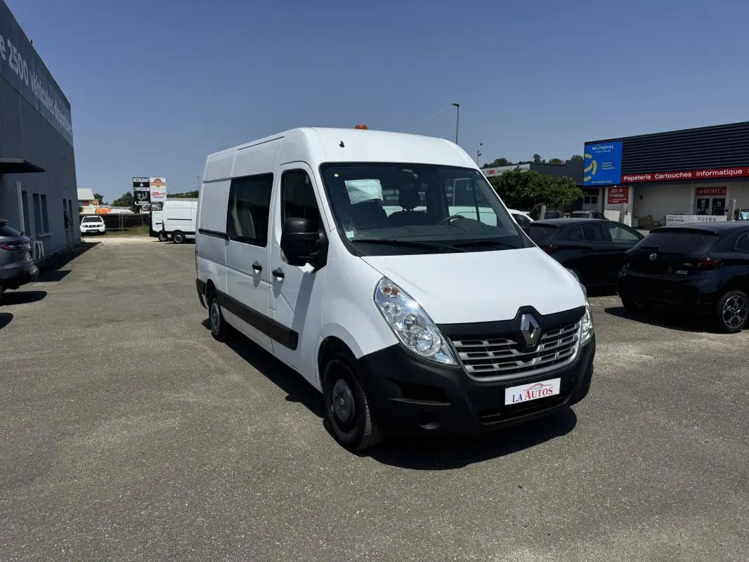 Renault Master blanc en vue 3/4 avant droit sur parking, avec calandre noire et logo Renault visible.
