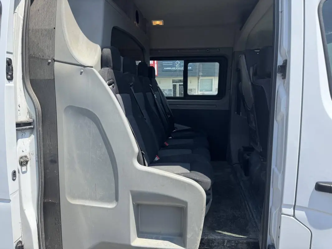 Intérieur du Renault Master blanc 2019, vue latérale sur la rangée de sièges passagers en tissu noir.