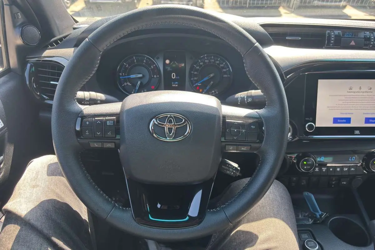 Vue rapprochée du volant cuir multifonctions du Toyota Hilux 2026 avec tableau de bord et écran multimédia JBL.