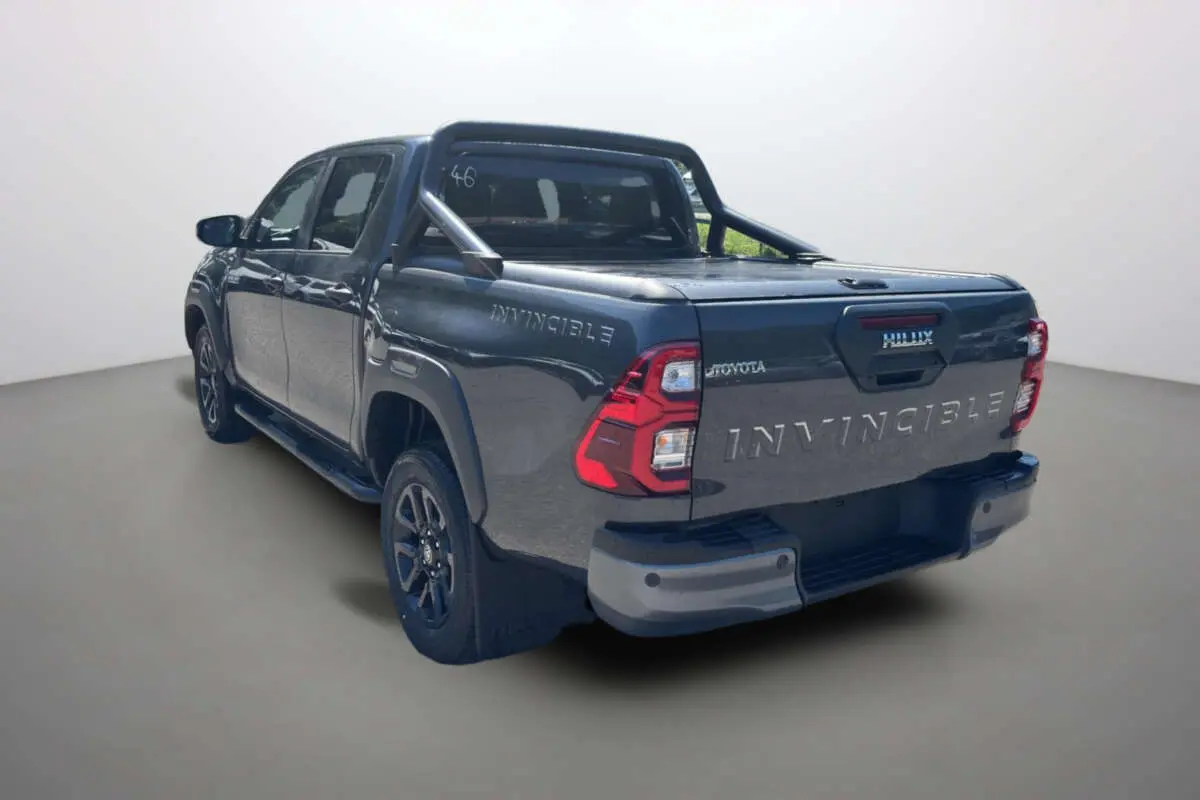 Toyota Hilux 4x4 gris atlas en 3/4 arrière droit, avec arceaux et rideau coulissant manuel sur la benne.