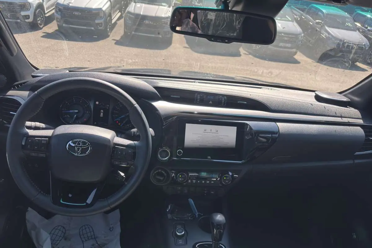 Vue intérieure du tableau de bord du Toyota Hilux 2026 gris atlas, volant cuir multifonctions et écran tactile central.