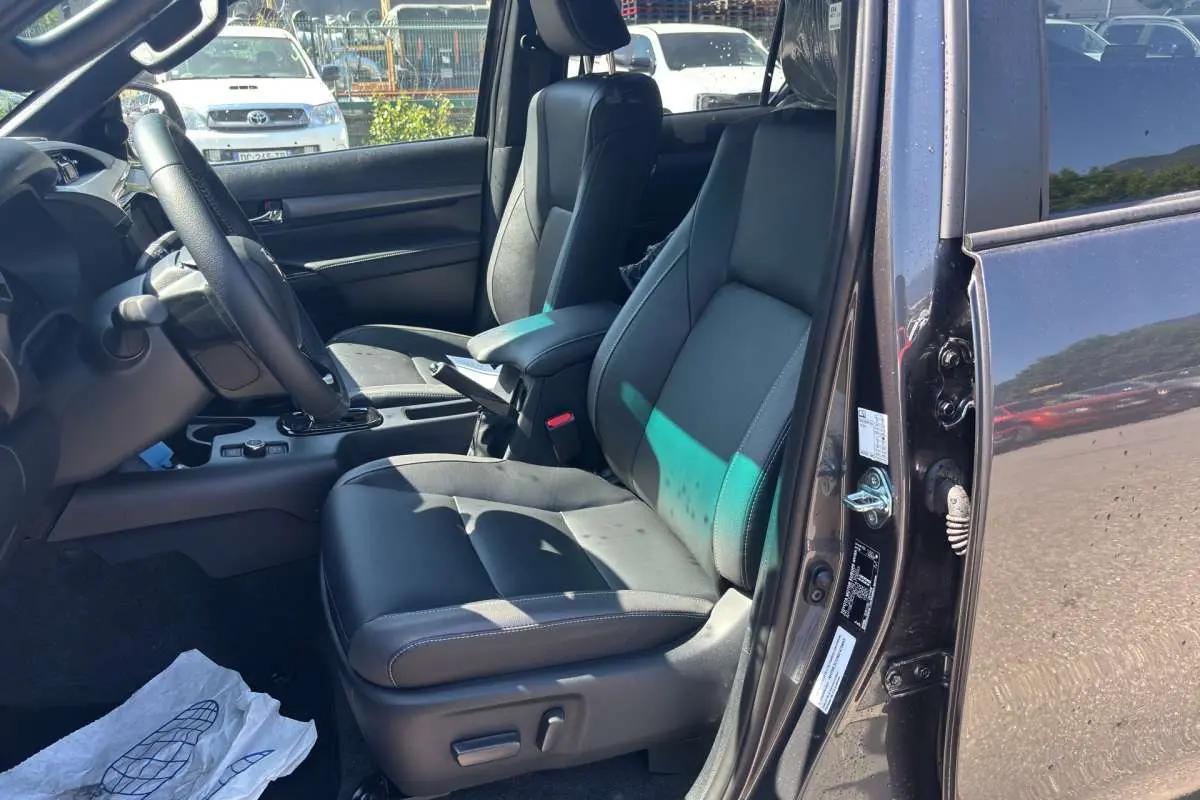 Vue intérieure côté conducteur du Toyota Hilux 4x4 gris atlas 2026, avec sièges cuir et volant multifonctions.