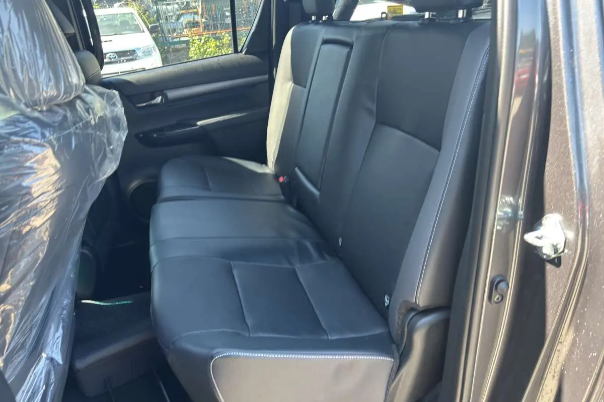 Vue intérieure côté droit montrant la banquette arrière en cuir noir du Toyota Hilux 4x4 gris atlas 2026.